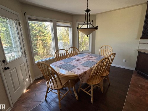 Dining area featuring bay windows, a glass-paneled exterior door, and a bronze-finish chandelier - 3516 49 Avenue, Drayton Valley, AB - Indoor Photo Showing Dining Room