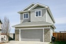 Two-story residence featuring light gray horizontal siding and a stone-clad garage facade - 62 Ellice Bend, Fort Saskatchewan, AB  - Outdoor 