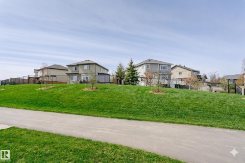 Expansive green space featuring a paved pathway, rolling grassy hills, and mature trees - 62 Ellice Bend, Fort Saskatchewan, AB - Outdoor