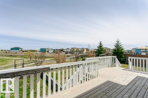 Expansive outdoor deck with white painted railings and steps, overlooking a green space - 62 Ellice Bend, Fort Saskatchewan, AB - Outdoor With Deck Patio Veranda