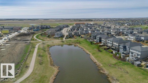 Neighborhood featuring a large body of water, paved walking paths, numerous residences with varied architectural styles, and a mix of developed and undeveloped land - 62 Ellice Bend, Fort Saskatchewan, AB - Outdoor With Body Of Water With View