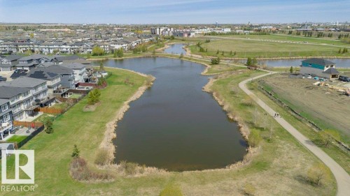 Aerial perspective showcasing a residential development bordering a naturalized pond system - 62 Ellice Bend, Fort Saskatchewan, AB - Outdoor With Body Of Water With View