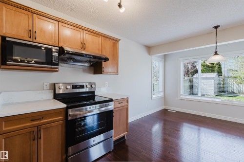 Kitchen and dining area featuring wood-finish flooring, light wood cabinetry, white countertops, and stainless steel appliances - 1140 115 Street, Edmonton, AB - Indoor Photo Showing Kitchen