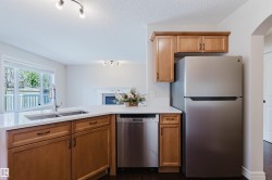 Kitchen featuring wood-finish cabinetry, stainless steel appliances, a double basin sink, and white countertops - 