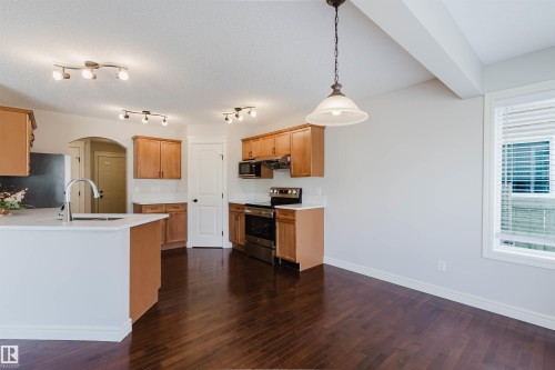 Open-concept kitchen and dining area featuring rich wood-finish flooring, light wood cabinetry, and white countertops - 1140 115 Street, Edmonton, AB - Indoor Photo Showing Kitchen