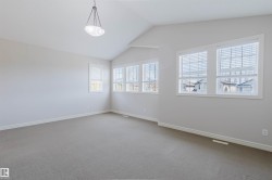 Spacious room featuring vaulted ceilings, neutral-toned walls, and plush carpeting - 