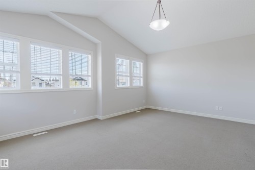Spacious room featuring vaulted ceilings, a contemporary ceiling light fixture, multiple windows with blinds, light-colored carpeting, and neutral wall tones - 1140 115 Street, Edmonton, AB - Indoor Photo Showing Other Room