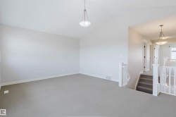 Spacious interior room featuring vaulted ceilings, light neutral wall paint, and gray carpet flooring - 