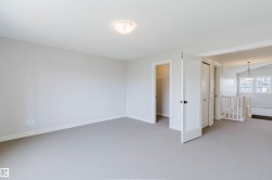 Spacious room with light gray carpeting, white baseboards, and a semi-flush ceiling light fixture - 