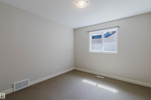 Neutral-toned room featuring a single window with white trim, a flush-mount ceiling light fixture, and textured carpeting - 1140 115 Street, Edmonton, AB - Indoor Photo Showing Other Room