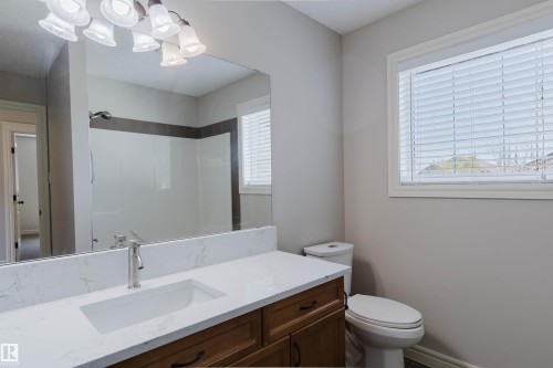 Bathroom featuring a single vanity with wood-finish cabinetry, a white countertop, and an integrated rectangular sink - 1140 115 Street, Edmonton, AB - Indoor Photo Showing Bathroom