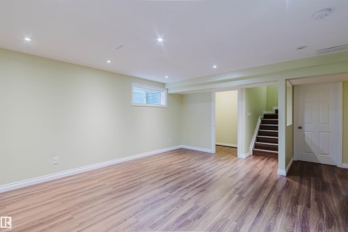 Spacious finished room featuring wood-finish flooring, recessed lighting, and a window with horizontal blinds - 1140 115 Street, Edmonton, AB - Indoor