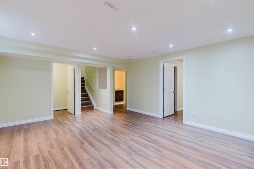 Spacious interior featuring wood-finish flooring, recessed ceiling lighting, light-toned walls, white trim, and multiple doorways - 1140 115 Street, Edmonton, AB - Indoor Photo Showing Other Room