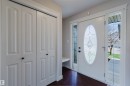 Entryway featuring a white door with an oval leaded glass insert, side lights, dark wood-finish flooring, and white bi-fold closet doors - 1140 115 Street, Edmonton, AB  - Indoor Photo Showing Other Room 