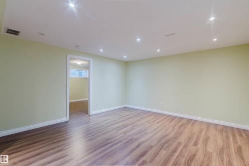 Spacious room with wood-finish flooring, recessed ceiling lighting, and light green painted walls with white baseboards - 1140 115 Street, Edmonton, AB - Indoor Photo Showing Other Room