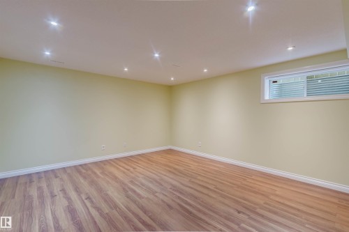 Spacious room featuring wood-finish flooring, recessed lighting, and a horizontal window with white trim - 1140 115 Street, Edmonton, AB - Indoor