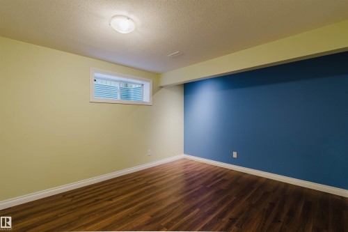 Room featuring wood-finish flooring, a contemporary ceiling light fixture, and a window with a white frame - 1140 115 Street, Edmonton, AB - Indoor Photo Showing Other Room