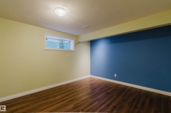 Room featuring wood-finish flooring, a contemporary ceiling light fixture, and a window with a white frame - 