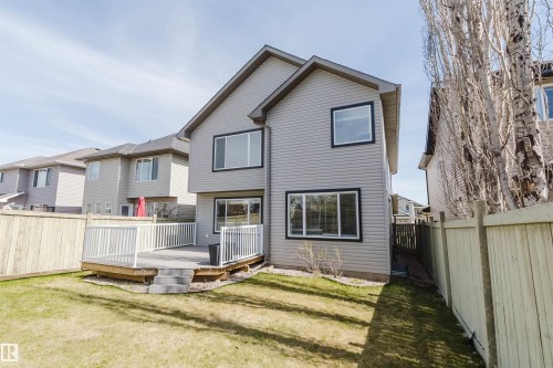 Rear exterior featuring gray siding, a composite deck with white railings, a sliding glass door, and multiple windows with dark trim - 1140 115 Street, Edmonton, AB - Outdoor
