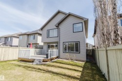 Rear exterior featuring gray siding, a composite deck with white railings, a sliding glass door, and multiple windows with dark trim - 