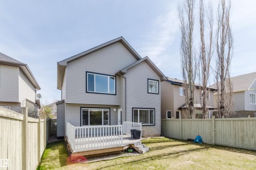Rear exterior featuring light gray siding, a white deck with steps, a wood fence, and a grassy yard - 1140 115 Street, Edmonton, AB - Outdoor