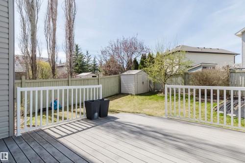 Spacious outdoor deck featuring light-toned composite decking and white railing, overlooking a fenced backyard with a lawn and storage shed - 1140 115 Street, Edmonton, AB - Outdoor With Deck Patio Veranda With Exterior