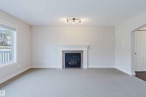 Living area featuring a fireplace with a white mantel and tile surround - 1140 115 Street, Edmonton, AB - Indoor Photo Showing Living Room With Fireplace