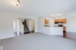Open-concept living area featuring light gray carpeting and an arched entryway - 