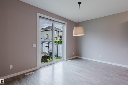 Spacious room featuring light wood-finish flooring, a contemporary drum pendant light fixture, and neutral wall paint - 7827 18 Avenue, Edmonton, AB - Indoor Photo Showing Other Room