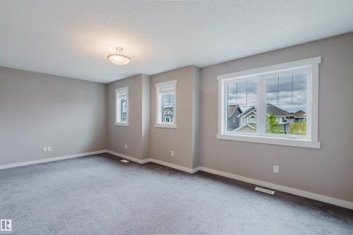 Expansive room featuring light gray wall paint and gray carpet flooring - 7827 18 Avenue, Edmonton, AB - Indoor Photo Showing Other Room