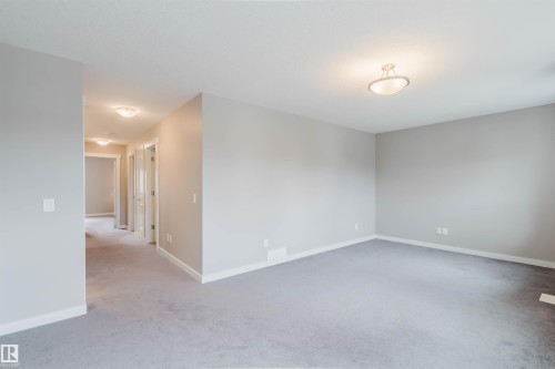Open room featuring light gray walls, light gray carpet, white baseboards, and a semi-flush mount ceiling light - 7827 18 Avenue, Edmonton, AB - Indoor Photo Showing Other Room