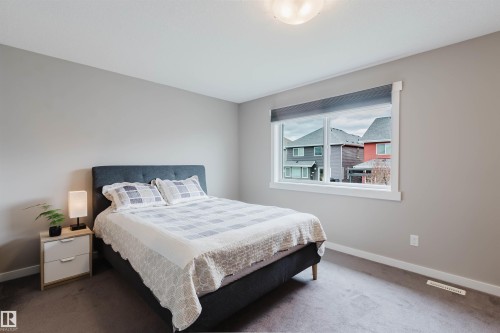 Carpeted room with a wide window featuring white trim and a roller shade - 7827 18 Avenue, Edmonton, AB - Indoor Photo Showing Bedroom