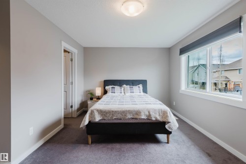 Bedroom featuring a large picture window, gray carpeting, neutral wall tones, white trim, and a flush mount ceiling light - 7827 18 Avenue, Edmonton, AB - Indoor Photo Showing Bedroom