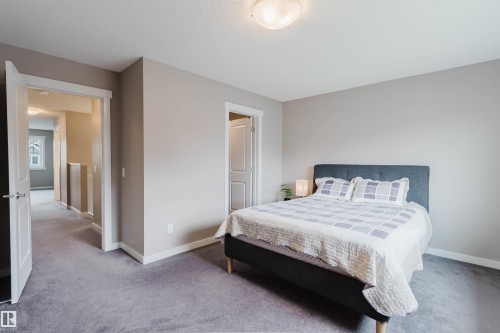 Carpeted room featuring a bed with a fabric headboard, neutral wall paint, and white trim - 7827 18 Avenue, Edmonton, AB - Indoor Photo Showing Bedroom