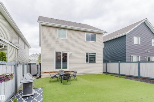 Rear exterior featuring light-colored siding, a sliding glass patio door, and multiple windows - 7827 18 Avenue, Edmonton, AB - Outdoor With Exterior
