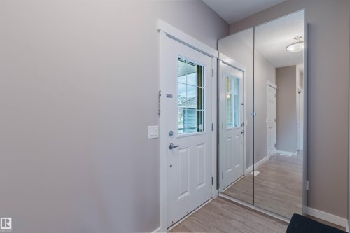 Entryway featuring light wood-finish flooring, white trim, and a full-height mirrored closet door - 7827 18 Avenue, Edmonton, AB - Indoor Photo Showing Other Room