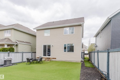 Private backyard featuring artificial turf, a small patio area with outdoor seating, and a wooden fence - 7827 18 Avenue, Edmonton, AB - Outdoor With Exterior