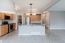 Kitchen featuring wood-finish cabinetry, stainless steel appliances, subway tile backsplash, and a central island with an integrated sink - 7827 18 Avenue, Edmonton, AB  - Indoor Photo Showing Kitchen With Double Sink 