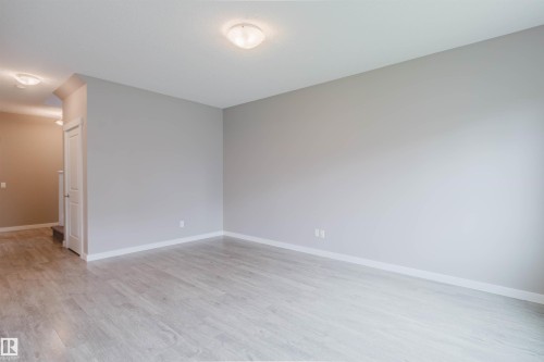 Spacious room featuring light wood-finish flooring, neutral gray walls, and white baseboards - 7827 18 Avenue, Edmonton, AB - Indoor Photo Showing Other Room