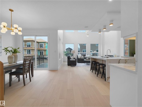 Open-concept living area featuring light wood-finish flooring, a contemporary kitchen island with a waterfall countertop, a dining area with a modern chandelier, and multiple large windows - 43 Eldridge Point(E), St. Albert, AB - Indoor Photo Showing Dining Room