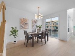 Bright dining area featuring light wood-finish flooring, a modern gold-finish chandelier, and white baseboards - 