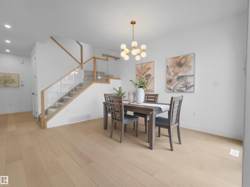 Dining area featuring light wood-finish flooring, a modern multi-bulb chandelier, and bright white walls - 43 Eldridge Point(E), St. Albert, AB - Indoor Photo Showing Dining Room