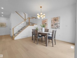 Dining area featuring light wood-finish flooring, a modern multi-bulb chandelier, and bright white walls - 