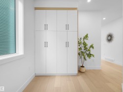 Built-in white cabinetry with matte black hardware and a light wood-finish accent - 
