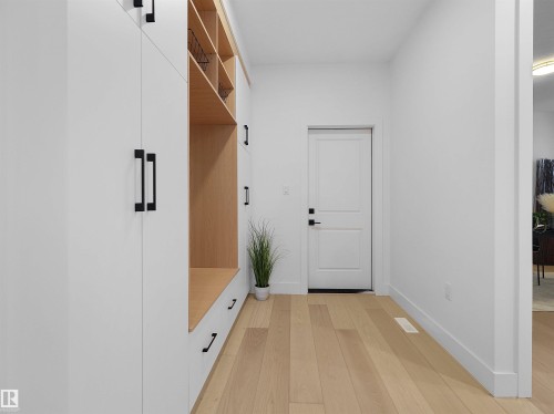 Built-in mudroom cabinetry featuring white fronts and matte black hardware, complemented by natural wood-finish cubbies and bench seating - 43 Eldridge Point(E), St. Albert, AB - Indoor Photo Showing Other Room