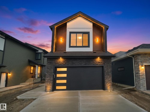 Contemporary facade featuring a prominent garage with decorative glass panels, stone veneer accents, and recessed lighting - 43 Eldridge Point(E), St. Albert, AB - Outdoor