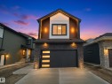 Contemporary facade featuring a prominent garage with decorative glass panels, stone veneer accents, and recessed lighting - 43 Eldridge Point(E), St. Albert, AB  - Outdoor 