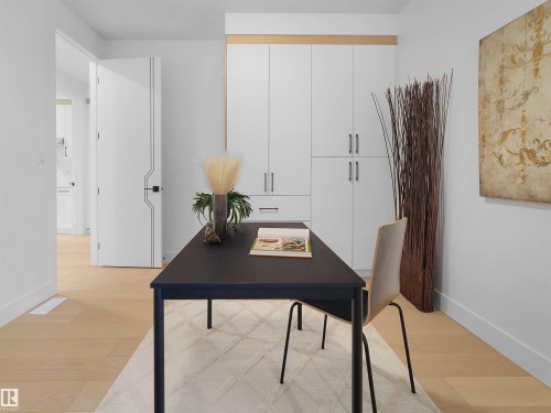 Dedicated office space featuring built-in cabinetry with modern hardware, light wood-finish flooring, and a contemporary door with a distinct linear design - 43 Eldridge Point(E), St. Albert, AB - Indoor Photo Showing Other Room