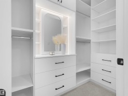 Custom white closet system featuring integrated lighting, multiple shelving units, hanging rods, and pull-out drawers with matte black hardware - 