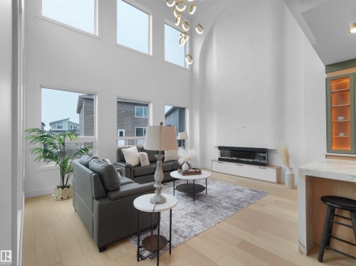 Two-story living area with high ceilings, light wood-finish flooring, and multiple large windows - 43 Eldridge Point(E), St. Albert, AB - Indoor With Fireplace